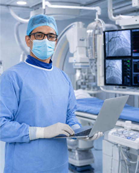 Cardiologist reviewing digital records on a laptop inside a Cath Lab